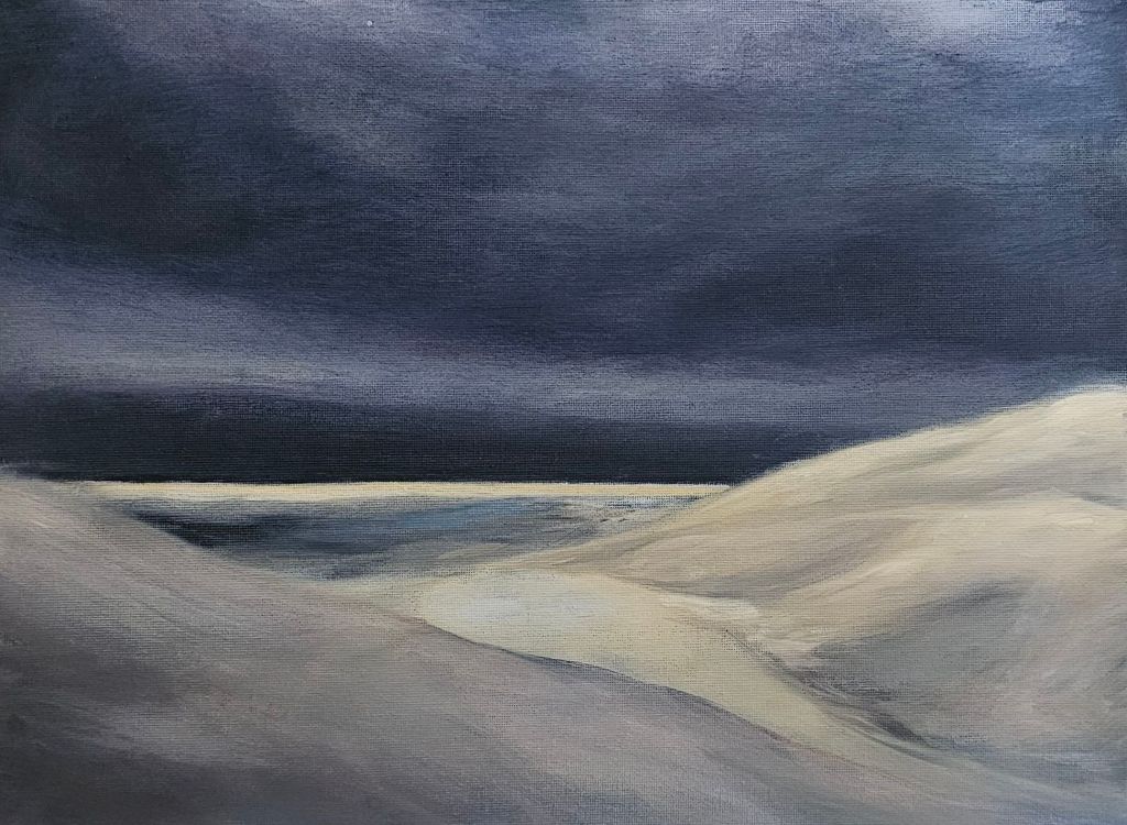 A restrained desert landscape in cool greys and muted blues, with soft dunes layered across the foreground. A pale ridge cuts diagonally through the sand toward a distant, dark horizon beneath a heavy, overcast sky, conveying silence and suspended movement.